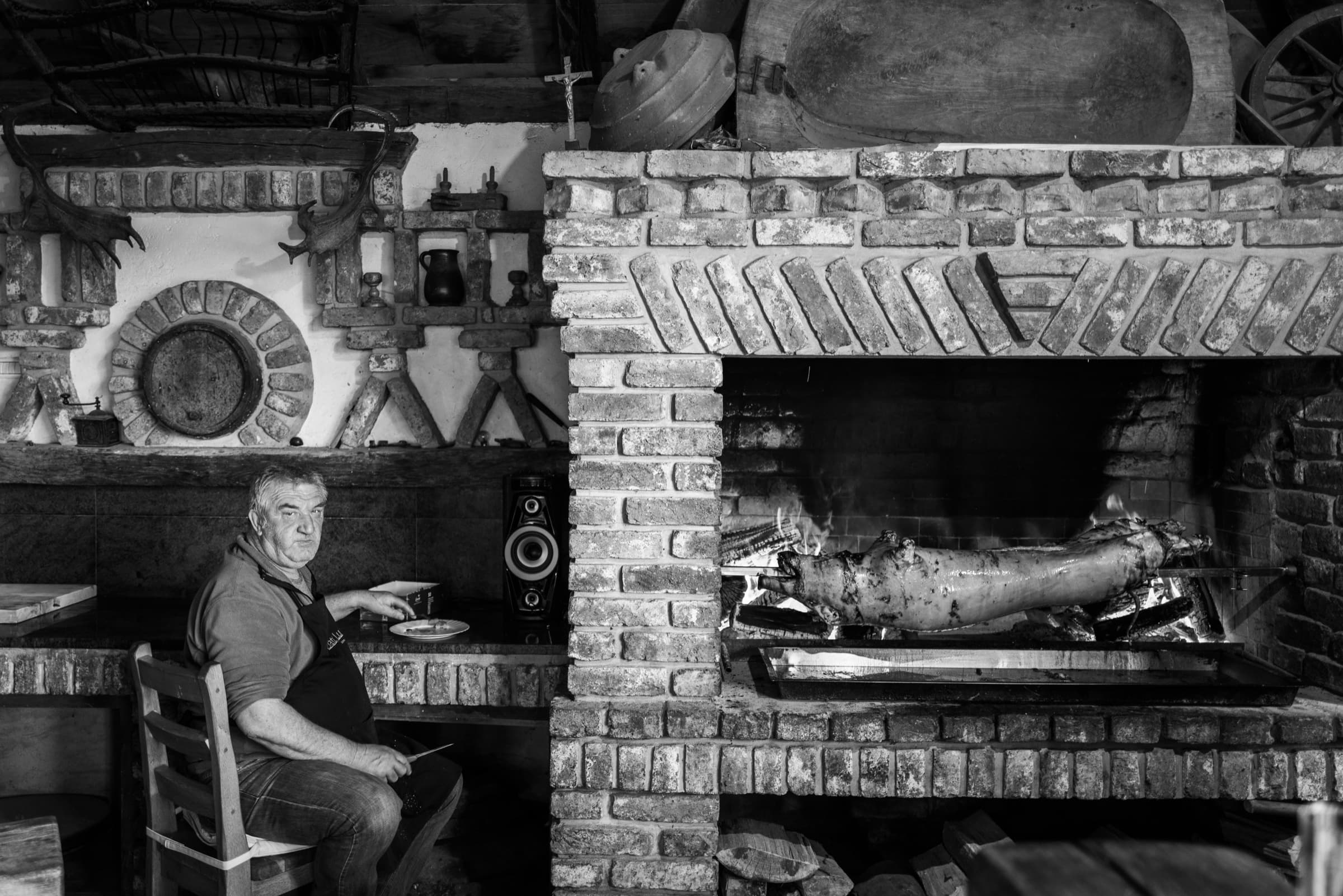 Man by a fireplace roasting a pig